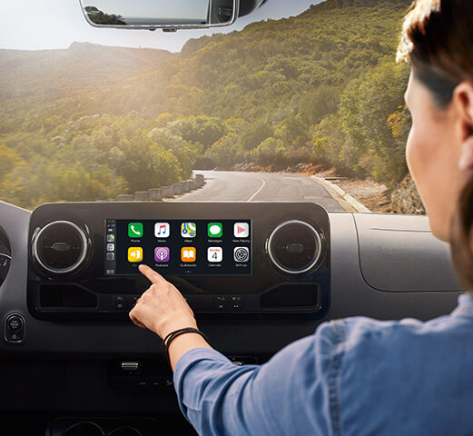 Personne en train d’utiliser les fonctions BluetoothMD et Apple CarplayMD à bord d’un fourgon Mercedes-Benz. 