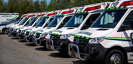 a line of parked Mercedes-Benz Ambulances in a lot.