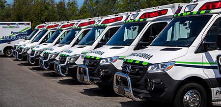 A line of parked Mercedes-Benz Ambulances in a lot.