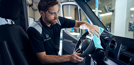 Mechanic cleaning the steering wheel of a Mercedes-Benz Van.