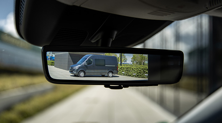 Conducteur d’un fourgon Sprinter de Mercedes-Benz regardant dans le rétroviseur numérique. 