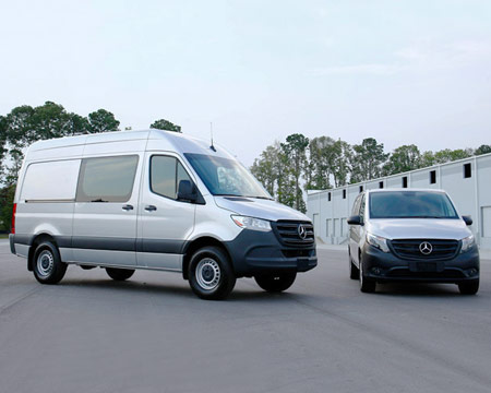 Fourgons Sprinter et Metris dans un parc de stationnement, prêts pour être aménagés. 